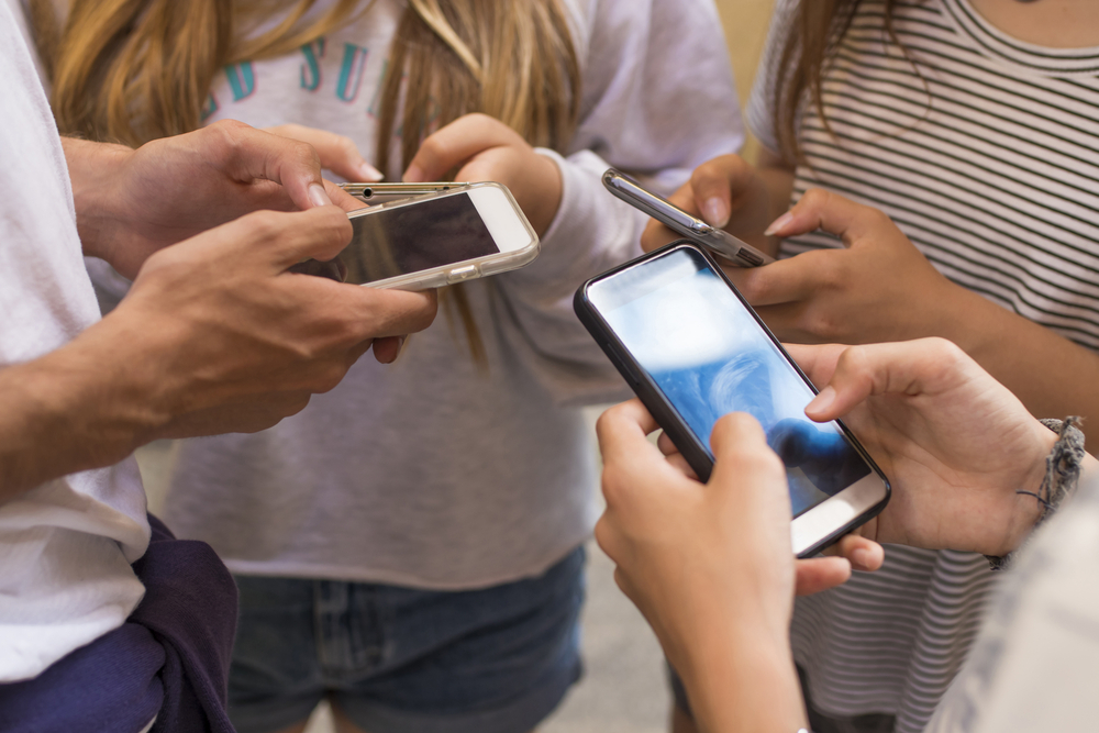 Young adults using smartphones in a circle social media and conn - Social Media Explorer